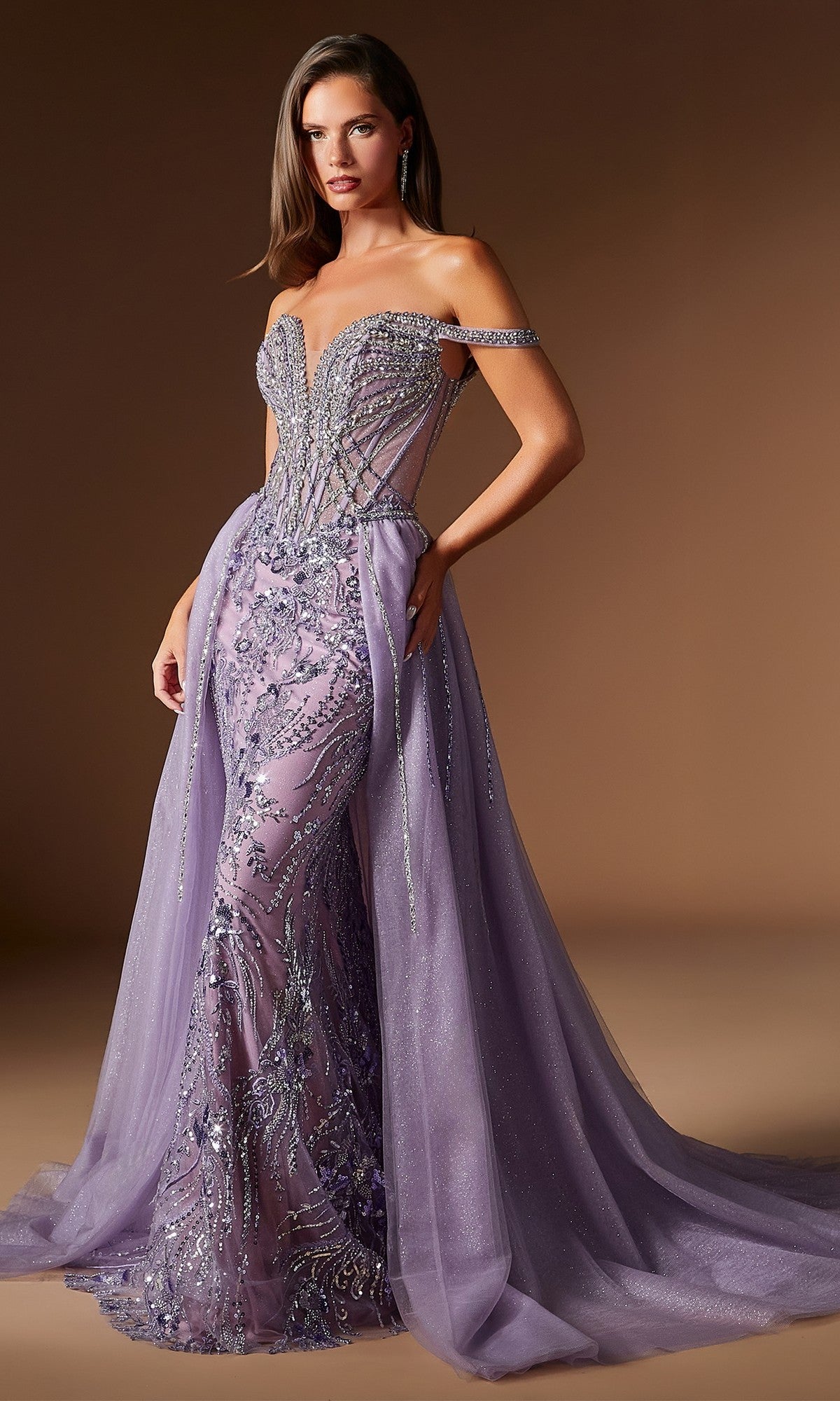 A woman wears the Ladivine CDS570 Long Prom Dress in English Violet, featuring strapless design, intricate beadwork, sheer panels, off-shoulder straps, and a flowing tulle overskirt—perfect for formal occasions.